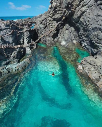 a person swimming in a body of water next to a cliff at Adeyu Tropical in Tarajalejo
