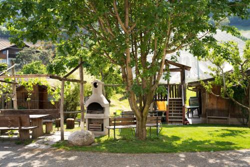 un parc avec un arbre, un banc et un bâtiment dans l'établissement Tribus Lorenz - Wiesgut, à Vollan