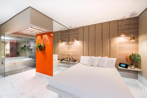 a bedroom with a large white bed and a bathroom at Motel Mood in Sao Paulo