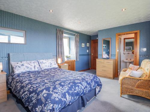 a blue bedroom with a bed and a chair at Braehead Croft in Portessie
