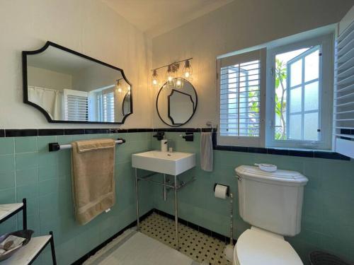a bathroom with a toilet and a sink and a mirror at Hot tub, tiki bar, outdoor shower, near Intercoastal Waterway! in West Palm Beach