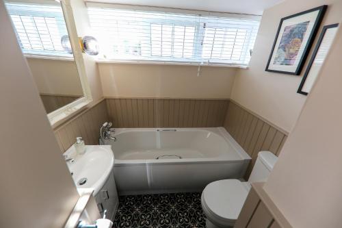 a bathroom with a tub and a toilet and a sink at Postbox Cottage in Melrose
