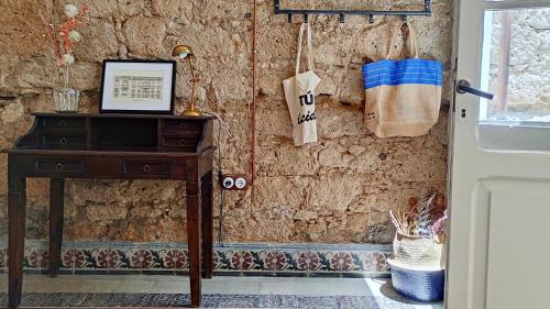 Habitación con mesa y pared de piedra con ventana. en Adara Vegueta Exclusive Apartment, en Las Palmas de Gran Canaria