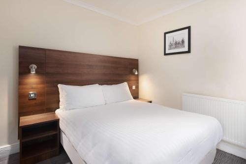 a bedroom with a large white bed with a wooden headboard at Best Western Carlton Hotel in Blackpool