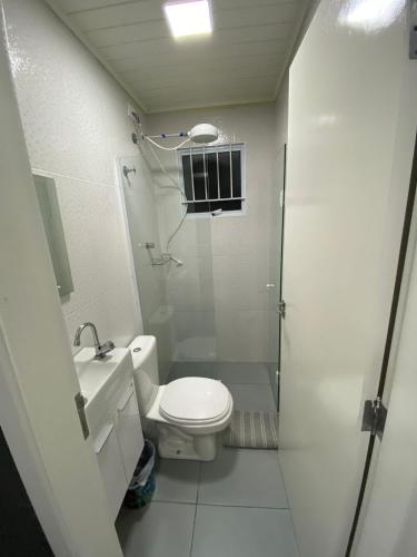 a white bathroom with a toilet and a shower at Apartamento aconchegante próximo Capivari in Campos do Jordão