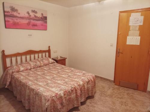 1 dormitorio con 1 cama y puerta de madera en Pensión- Mari Loli - Oficial en Guardamar del Segura