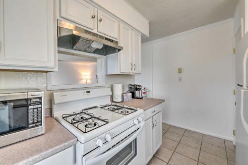 a kitchen with white cabinets and a stove top oven at Brigantine Condo with Gas Grill - Walk to Beach! in Brigantine