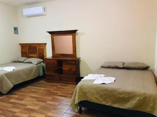 a room with two beds and a dresser with a mirror at Hotel del Carmen in Retalhuleu