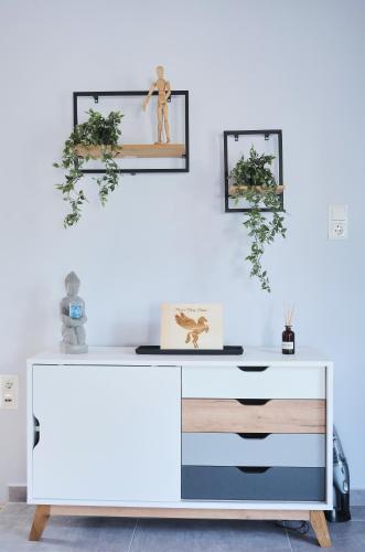 a white dresser against a white wall with two framed pictures at Pegasus' Glory House in Kavala
