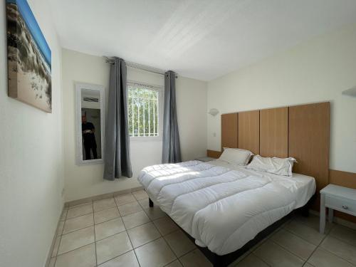 a bedroom with a large white bed and a window at Appartement 321 avec deux chambres - LES SUITES DE ROBINSON - Résidence avec piscine en bord de Siagne, à Mandelieu-La-Napoule in Mandelieu-la-Napoule