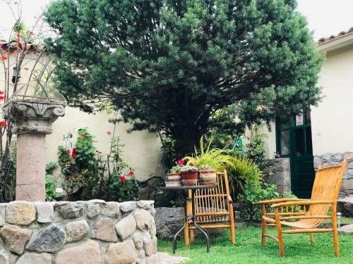 a table and two chairs in a yard with a tree at Hospedaje La Florida in Urubamba