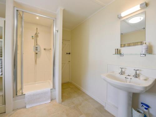 a white bathroom with a sink and a shower at Agar Cottage in Port Isaac
