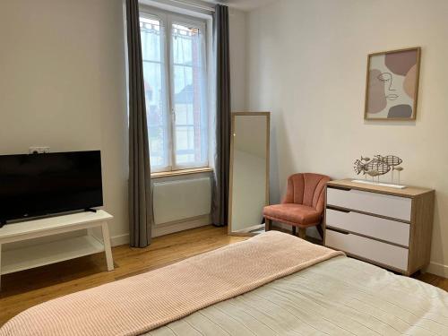 a bedroom with a bed and a tv and a chair at Superbe appartement proche port Guillaume in Dives-sur-Mer