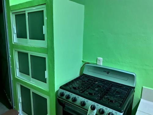 una cucina con piano cottura e parete verde di CASA CERCA DE LA PLAYA a Puerto Escondido