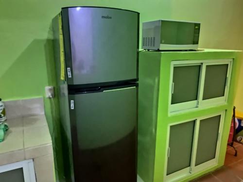 een groene koelkast naast een magnetron in een keuken bij CASA CERCA DE LA PLAYA in Puerto Escondido
