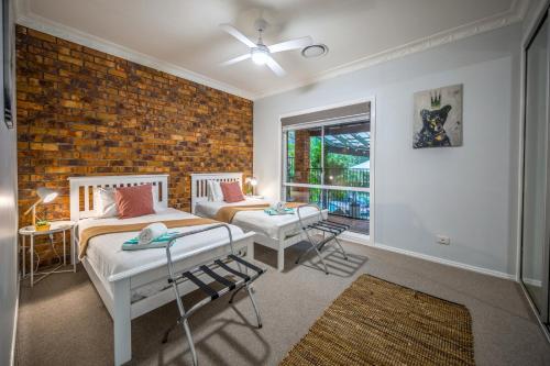 a bedroom with two beds and a brick wall at The Hillside Retreat in Mount Tamborine