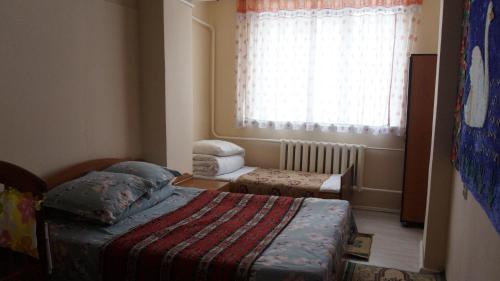 a small bedroom with two beds and a window at RAHAT Guest House & Hostel in Toktogul in Toktogul