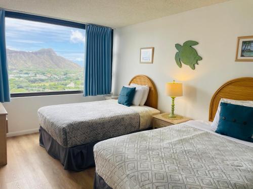 a hotel room with two beds and a large window at Waikiki Banyan 3411 Ocean View - FREE PARKING in Honolulu