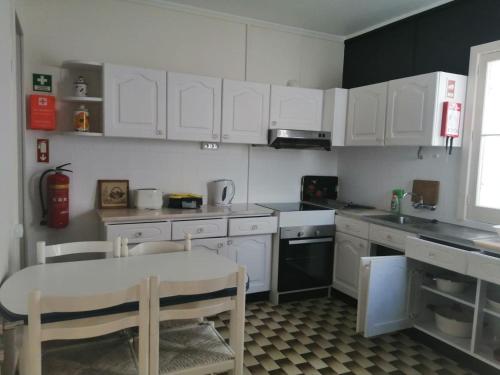 a kitchen with white cabinets and a table and chairs at House of Roses in Ponta Delgada