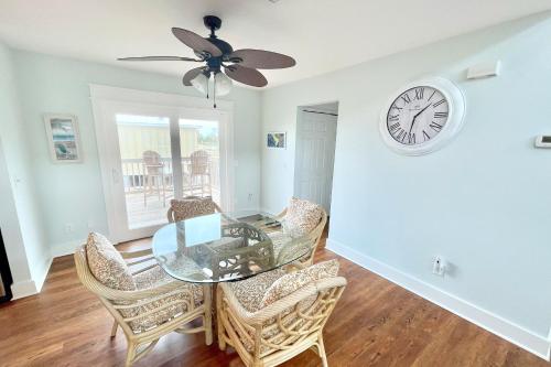 a dining room with a glass table and chairs and a clock at Shore Bird in Port Saint Joe