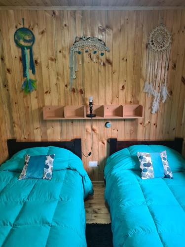 two beds in a room with wooden walls at Montblanc in Las Trancas