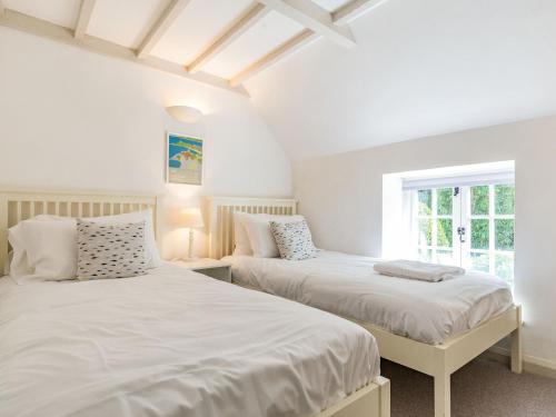 2 bedden in een slaapkamer met witte muren en een raam bij 3 Rose Cottages in St. Agnes 