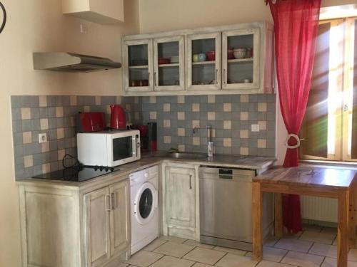 une cuisine avec un lave-linge et un micro-ondes dans l'établissement Maison confortable avec balcon au cœur de Cadouin, proche de Dordogne et grands sites touristiques - FR-1-616-196, au Buisson de Cadouin
