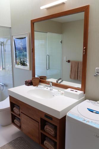 uma casa de banho com um lavatório e um espelho grande em 読谷目黒や em Jima