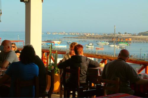 a group of people sitting at a table looking at the water at El Gamonal - Paracas in Paracas