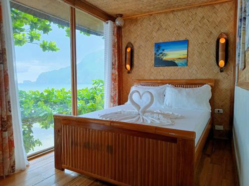Cama en habitación con ventana grande en Hut Sunset Island View, en El Nido