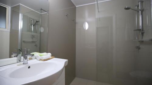 a white bathroom with a sink and a shower at Whitsunday Sands Resort in Bowen