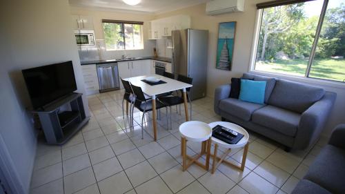 a living room with a couch and a table and a kitchen at Whitsunday Sands Resort in Bowen