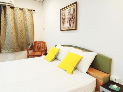 a bedroom with a white bed with yellow pillows at house 1 for 6 paxs whole house 3 beds in Hat Yai