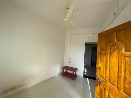 Habitación con puerta de madera y mesa roja. en Shree Sadguru Krupa Yatri Niwas, en Kolhapur