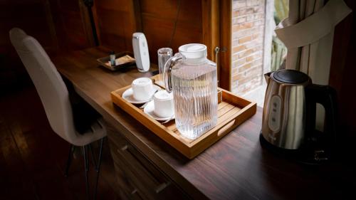 a counter with a coffee maker and cups on a table at Kusfarm Bali by AHM in Selemadeg