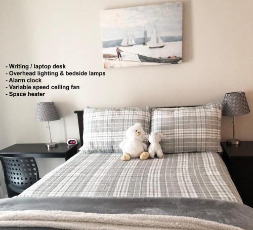 Dois ursos de peluche sentados em cima de uma cama em Tempe ASU Guest Suite em Tempe