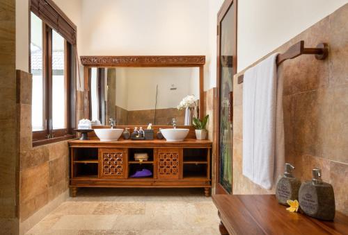a bathroom with two sinks and a large mirror at Swan Paradise A Pramana Experience in Gianyar