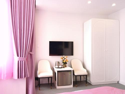 a room with two chairs and a table with a tv at Free Style Hotel Dalat in Da Lat