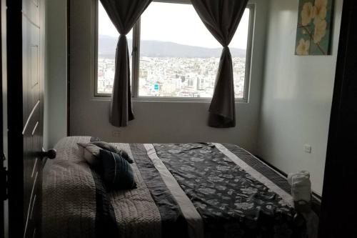 een slaapkamer met een bed en uitzicht op de stad bij Hermosa Casa Vacacional en Ambato sector Pinllo CON UNA VISTA ÚNICA DE LA CIUDAD in Ambato