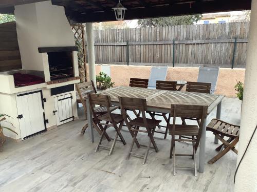 une table et des chaises en bois sur une terrasse avec une cuisinière dans l'établissement Sur le quai de port fréjus, à Fréjus