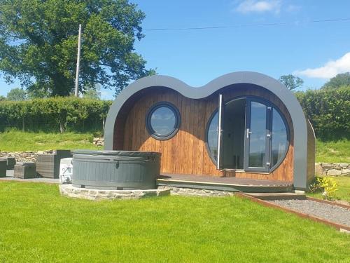 a house shaped like a dog with a round window at Great House Farm Luxury Pods and Self Catering in Crickadarn