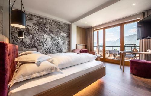 una camera da letto con un letto grande e una grande finestra di Marini's giardino Hotel a Tirolo