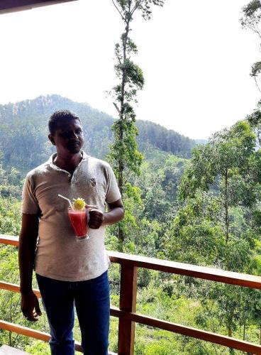 a man standing on a balcony with a drink at Barn Hills in Ella
