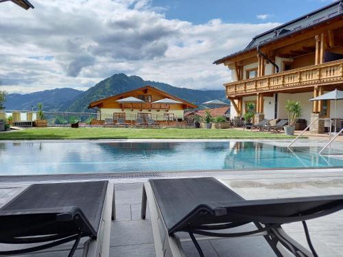 a swimming pool with two chairs and a house at Pension Edelweiß in Sankt Johann im Pongau