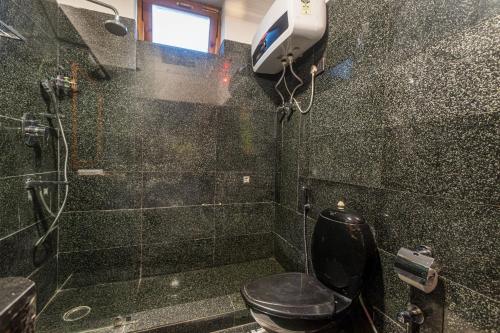 a bathroom with a black toilet and a shower at SaffronStays Monarch Manor, Manali - regal mansion in Manāli