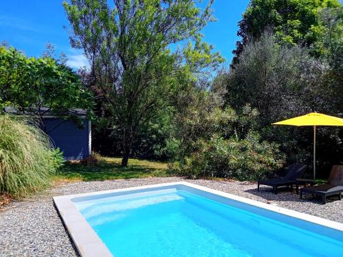 a swimming pool in a yard with an umbrella at Appartement RDC Le Brin de soleil, Gite l Echapée Belle in Aubenas