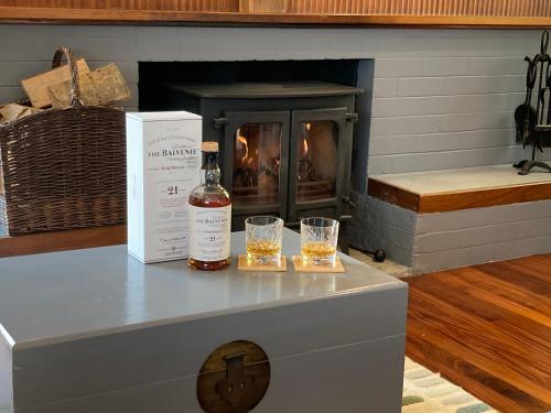 a bottle of whiskey and two glasses on a table with a fireplace at Craigneuk near Oban, stunning home with sea views in Oban