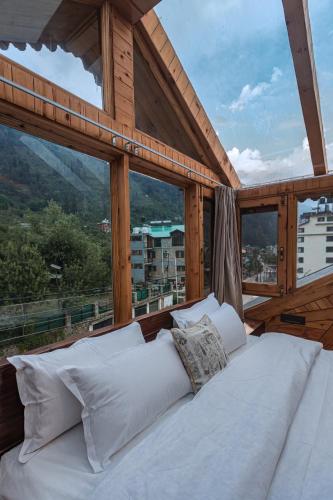 a bed in a room with a large window at SaffronStays Monarch Manor, Manali - regal mansion in Manāli