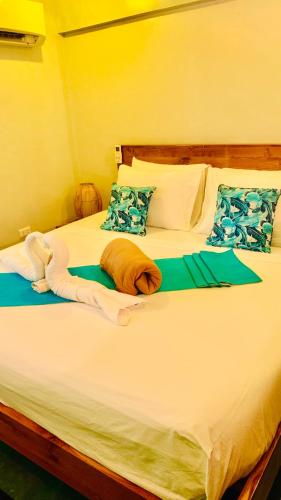 a large bed with white sheets and blue pillows at Hidden of Cailan Inn in El Nido