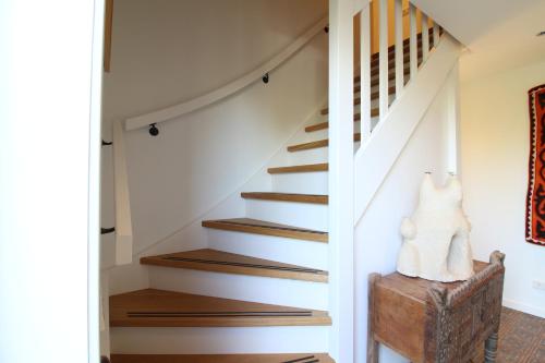 a staircase in a house with a cat sitting on a chest at Ollediek in Houwerzijl